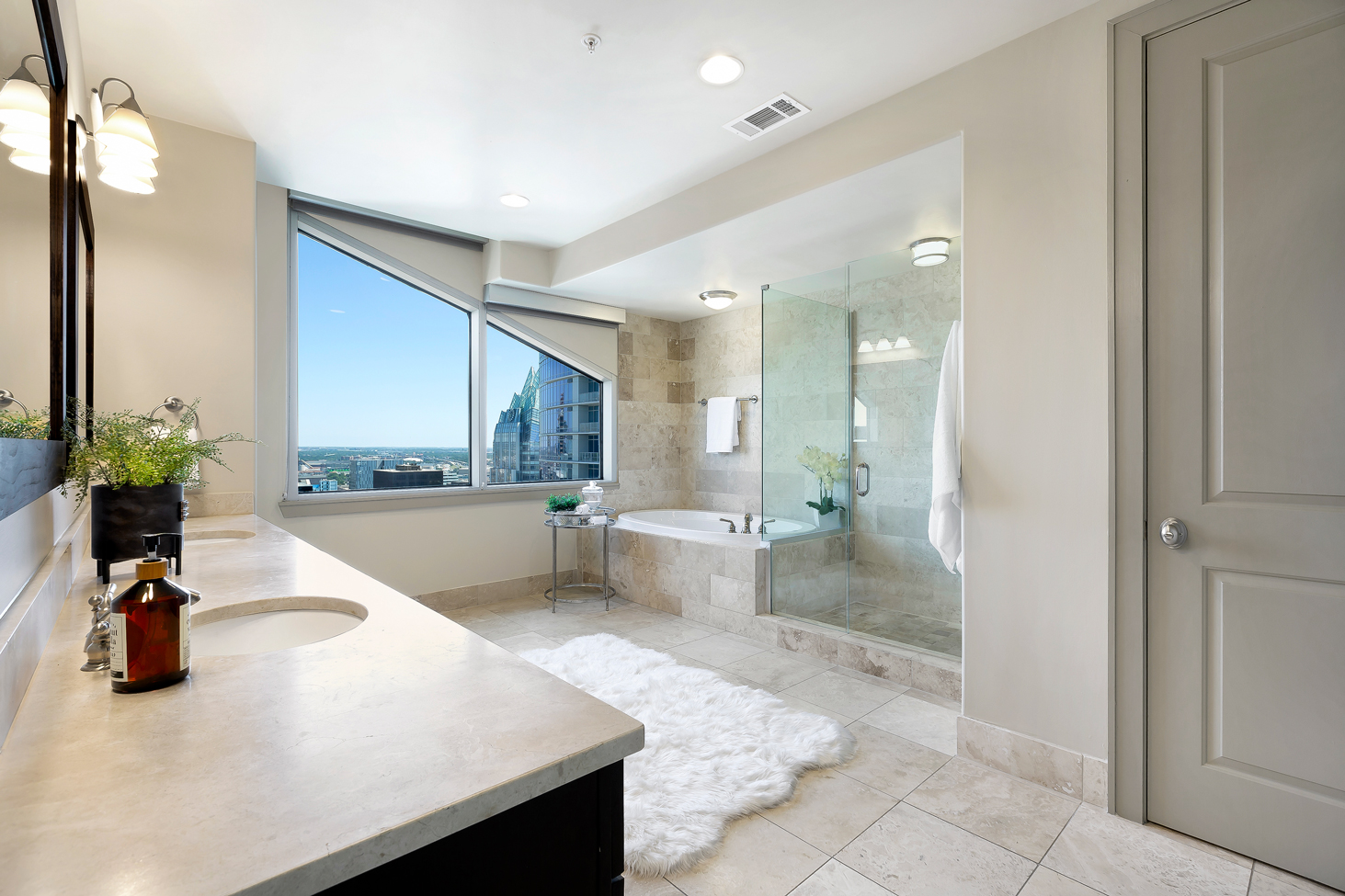 Spa-inspired bathroom with travertine flooring at Ashton Austin's penthouse apartments for rent	